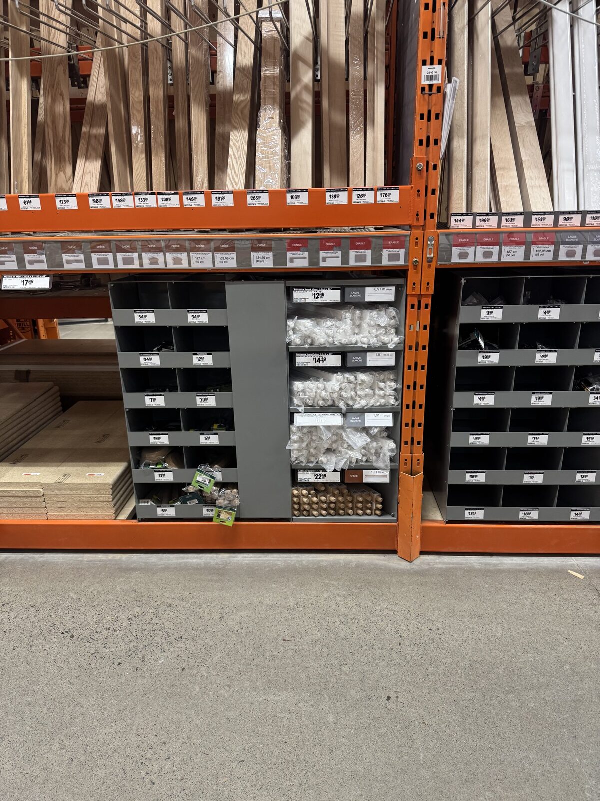 The display installed in a Home Depot aisle, its labelled compartments holding stair hardware below racked lumber