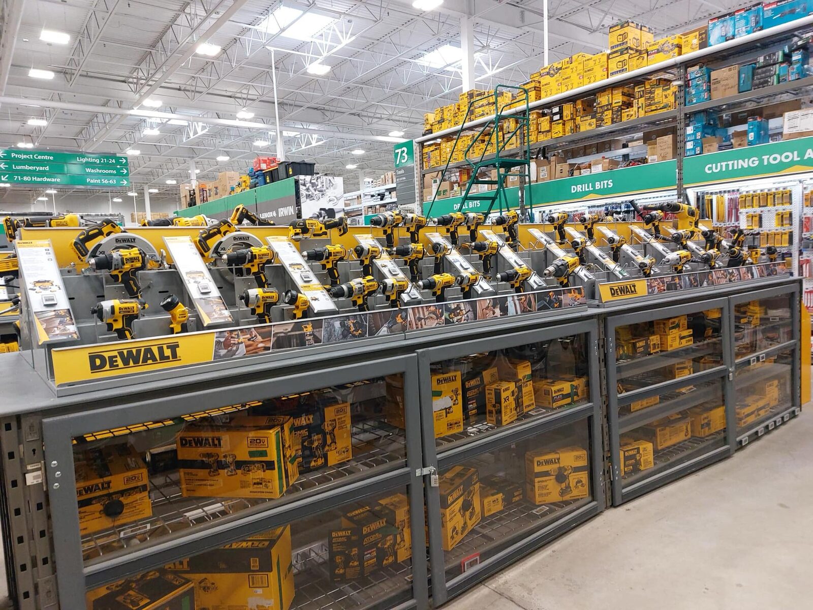 A long unbroken run of DeWalt tools on the display deck above glass-door cabinets of boxed stock